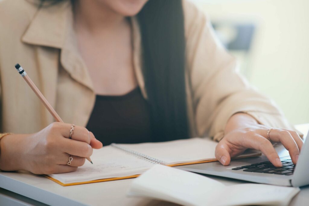 Person researching on computer with notebook.