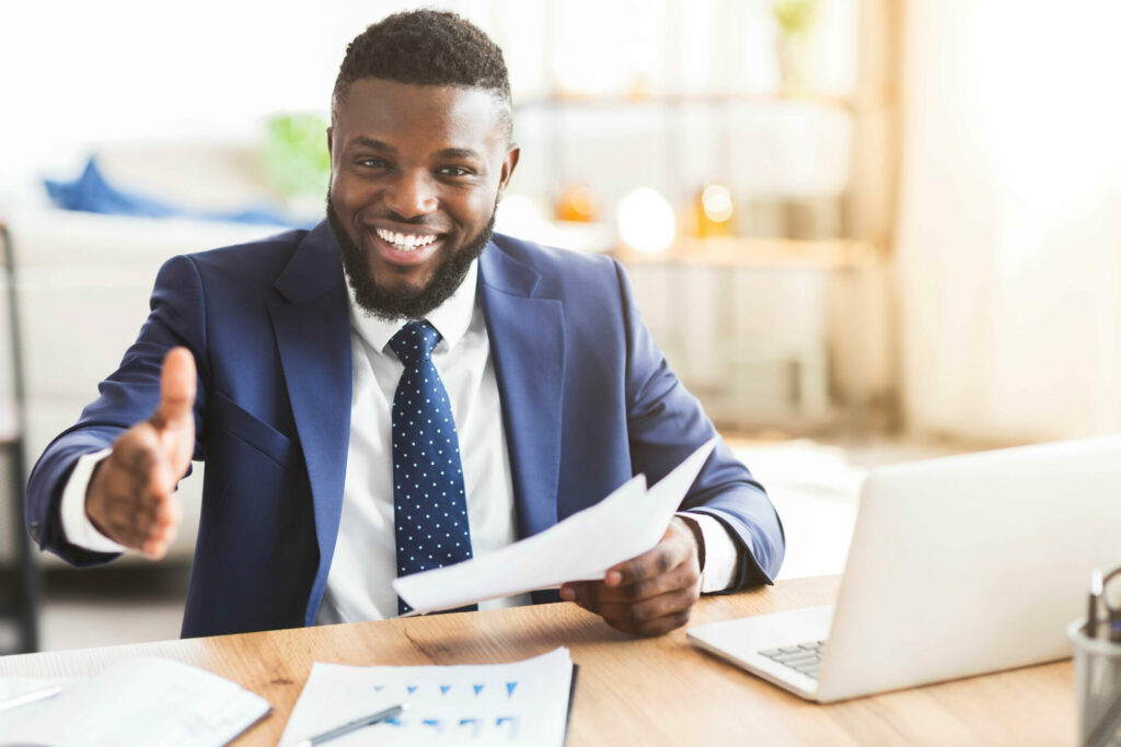 Smiling person in dress clothes extending their hand.